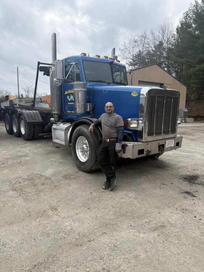 Ironclad Recycling owner standing beside the company roll-off truck